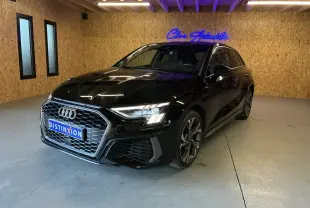 Audi A3 Sportback noir vue 3/4 avant droit en intérieur, avec calandre hexagonale et phares LED allumés.