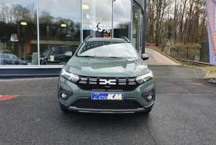 Vue frontale d'un Dacia Jogger 2024 hybride en vert lichen avec barres de toit et calandre noire.