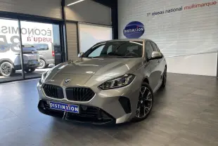 BMW Série 1 120d M Sport gris en 3/4 avant dans un showroom avec jantes 18 pouces bicolores et calandre noire.
