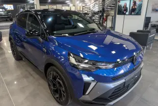 Vue 3/4 avant droite du Renault Captur E-TECH Full Hybrid 2025 en bleu Iron avec toit noir dans un showroom.