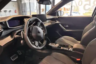 Intérieur du Peugeot 2008 gris 2025, vue côté conducteur, volant multifonction et écran central moderne.