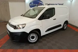 Vue 3/4 avant droit d’un utilitaire Citroën Berlingo blanc avec pare-chocs noirs et jantes acier en intérieur showroom.