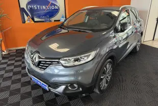 Renault Kadjar gris en 3/4 avant droit, avec jantes alliage et calandre distinctive dans un showroom.