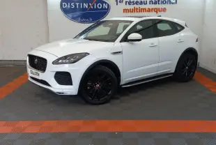 Jaguar E-PACE blanc vue 3/4 avant droit, roues noires, dans un showroom avec sol gris et bandes orange.