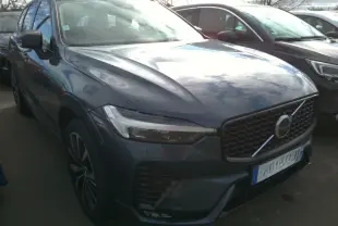Vue 3/4 avant droite d'un Volvo XC60 bleu avec calandre noire laquée et jantes alliage 20 pouces bicolores.