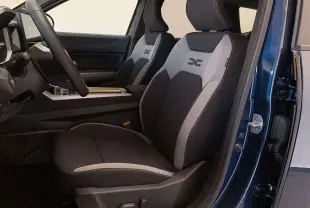 Vue intérieure côté conducteur du Dacia Bigster Hybrid 155 Journey Plus 2026, sièges tissu noir et gris avec logo X brodé.