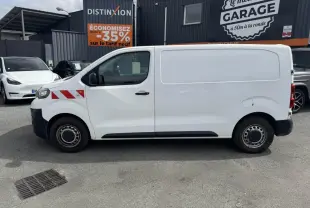 Profil droit d'un utilitaire blanc Peugeot Expert Fourgon 2018 avec bandes rouges diagonales sur l'aile avant.