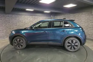 Vue de profil côté gauche d'un FIAT 600 1.2 Hybrid bleu métallisé avec jantes alliage et toit noir en intérieur showroom.