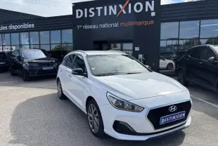 Hyundai i30 SW blanche vue 3/4 avant droit devant un showroom Distinxion avec jantes alliage 17 pouces.