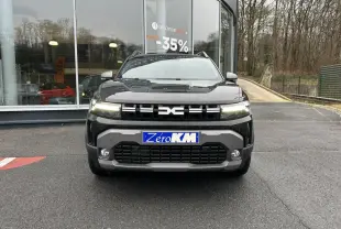 Vue frontale du Dacia Duster noir métallisé 2025 avec signature lumineuse LED et plaque Zéro KM visible.