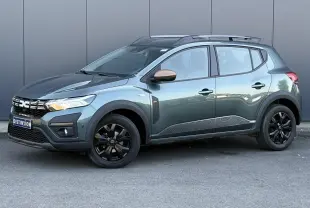Dacia Sandero Stepway 2025 vert cèdre en 3/4 avant droit avec jantes noires et barres de toit grises.
