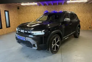 Dacia Duster 1.6 Hybrid noir en 3/4 avant droit, avec jantes noires et grises, dans un intérieur bois clair.