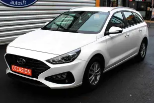 Hyundai i30 SW blanc polaire vue 3/4 avant droit, avec calandre noire et plaque "OCCASION" rouge visible.