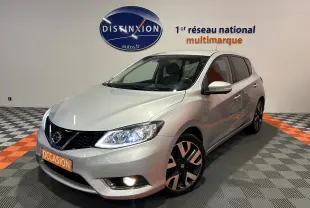 Nissan Pulsar gris vue 3/4 avant droit avec phares allumés et jantes alliage noires et argentées.