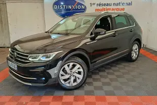 Volkswagen Tiguan noir vu en 3/4 avant droit dans un showroom avec sol à damier gris et rouge.