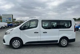 Profil côté gauche d'un Renault Trafic Fourgon blanc 2016 avec porte latérale coulissante et vitres arrière vitrées.