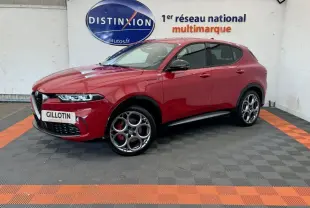 Vue 3/4 avant gauche d'un Alfa Romeo Tonale rouge avec jantes spécifiques et étriers de frein rouges sur fond intérieur showroom.