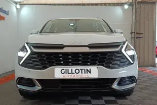 Vue frontale d’un KIA Sportage blanc 2022 avec calandre noire et feux LED en forme de flèche allumés.