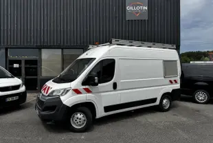 Vue 3/4 avant droit d’un utilitaire Citroën Jumper blanc avec bandes rouges réfléchissantes et galerie sur le toit.
