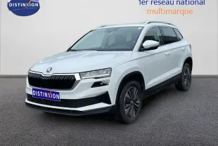Vue 3/4 avant d’un Skoda Karoq blanc glacier avec calandre noire et jantes bi-ton, sur fond neutre extérieur.