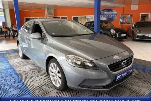 Volvo V40 gris vue 3/4 avant droit en intérieur, avec calandre distinctive et plaque Distinxion visible.