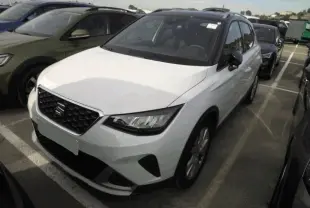 SEAT Arona blanc Nevada en 3/4 avant droit, avec calandre noire et toit noir contrasté visible.