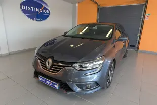 Renault Mégane IV gris en 3/4 avant droit, avec calandre chromée et jantes alliage bicolores en showroom.