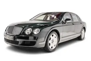 Vue 3/4 avant droite d'une Bentley Continental Flying Spur vert foncé avec calandre chromée et jantes blanches.