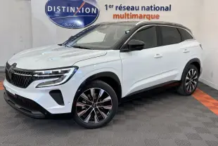Vue 3/4 avant droite du Renault Austral blanc avec jantes alliage et toit noir dans un showroom multimarque.