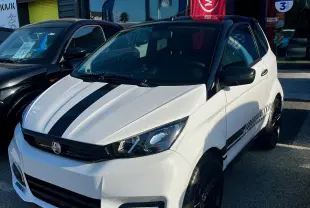 Vue 3/4 avant droite d'une AIXAM City Sport blanche avec toit noir et jantes noires, stationnée devant un concessionnaire Ligier.