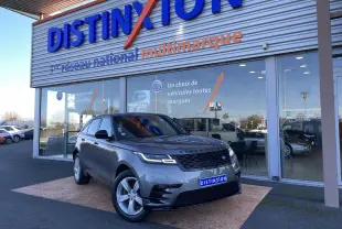 Range Rover Velar D240 S R-Dynamic gris Corris en 3/4 avant droit devant un showroom Distinxion.