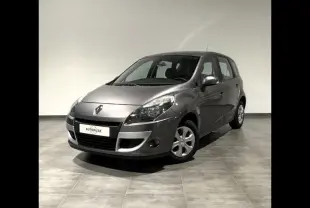 Renault Grand Scenic gris en 3/4 avant droit, montrant ses phares et jantes alu dans un intérieur neutre.