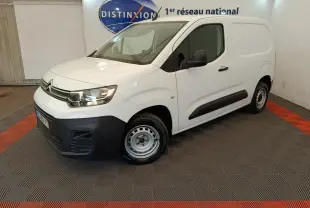 Vue 3/4 avant droit d'un Citroën Berlingo blanc 2022 avec pare-chocs noir et jantes acier en intérieur showroom.