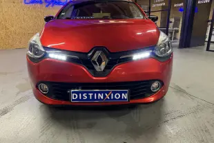 Vue frontale d'une Renault Clio Estate IV rouge avec feux diurnes allumés et plaque Distinxion visible.