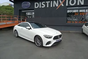 Mercedes Classe E Coupé 220D AMG Line blanc vu en 3/4 avant droit, avec calandre AMG et jantes alliage 19 pouces.