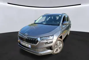 Vue 3/4 avant d'un Skoda Karoq gris métallisé avec calandre chromée et jantes alu 17 pouces sur fond neutre.