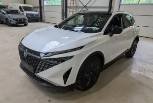 Nissan Qashqai blanc nacré en 3/4 avant droit, avec calandre noire et jantes alliage 19 pouces Aero.