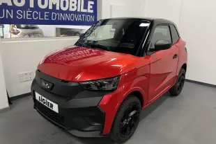 Vue 3/4 avant d'une Ligier JS50 BEV 8KWH Elite rouge avec toit noir et jantes alu noires en intérieur showroom.