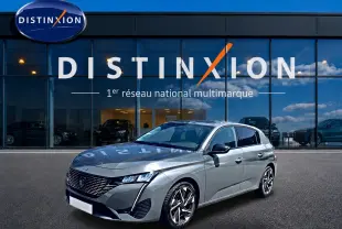 Peugeot 308 gris vue 3/4 avant droit, avec calandre distinctive et jantes alliage modernes, devant showroom Distinxion.