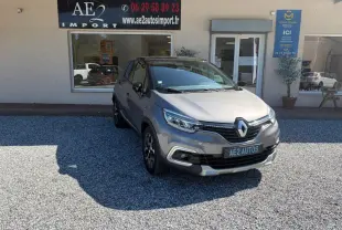 Renault Captur gris 3/4 avant droit, jantes alliage et calandre noire, stationné devant un garage AE2 Autos.