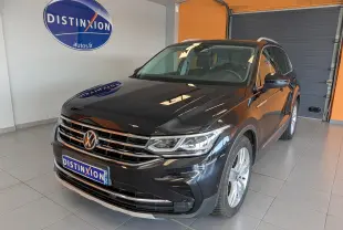 Volkswagen Tiguan noir 2.0 TDI 150ch vue 3/4 avant droit en intérieur avec logo Distinxion en arrière-plan.