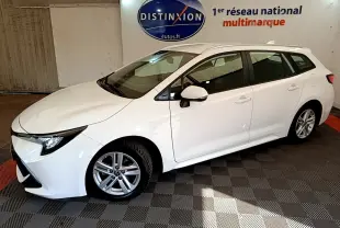 Toyota Corolla Hybride 122h Dynamic Business blanc vue de profil côté gauche en intérieur avec rails de toit chromés visibles.