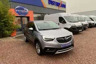 Opel Crossland X gris métallisé en 3/4 avant droit, garé devant un concessionnaire Distinxion.