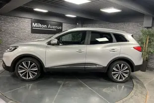 Renault Kadjar gris platine vu de profil côté gauche, avec jantes alliage 19 pouces et attelage fixe visible.