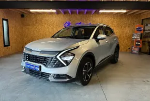 KIA Sportage hybride gris 2024 vu en 3/4 avant droit, avec calandre noire et jantes distinctives.