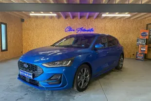 Ford Focus 1.0 EcoBoost bleu en 3/4 avant droit, avec calandre hexagonale et jantes alliage visibles.