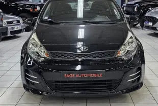 KIA RIO III noire vue 3/4 avant droit en showroom, avec jantes blanches et calandre caractéristique.