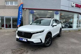 Honda CR-V 2024 blanc platine nacrée en 3/4 avant droit, avec jantes noires et toit panoramique visible devant concession.