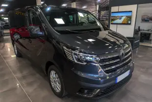 Renault Trafic Combi gris comète en 3/4 avant droit, intérieur showroom avec éclairage et reflet au sol.