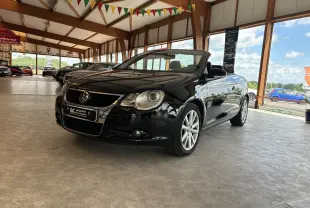 Volkswagen EOS cabriolet noir vue 3/4 avant droit dans un showroom lumineux avec toit en bois apparent.